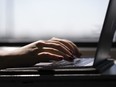 A woman types on a laptop on a train in New Jersey on May 18, 2021. The Weather Network and MétéoMédia still can't send weather alerts through push notifications from its app following a "malicious cyberattack" on Monday.