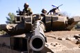 Israeli soldiers sit on a Merkava tank