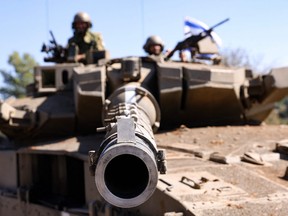 Israeli soldiers sit on a Merkava tank