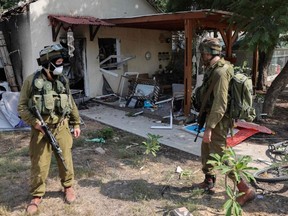 Israeli soldiers inspect the damage caused by rocket attacks from the Gaza Strip in the southern Israeli kibbutz of Kfar Aza on the border with the Palestinian territory, Tuesday, Oct. 10, 2023.
