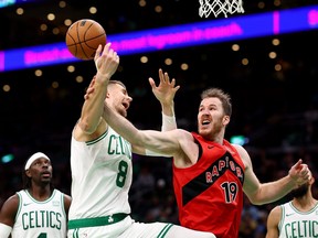 Jakob Poeltl (19) of the Toronto Raptors fouls Kristaps Porzingis (8) of the Boston Celtics