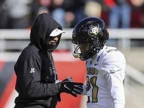 Colorado head coach Deion Sanders and Colorado safety Shilo Sanders (21) speak before an NCAA college football game against Utah, Saturday, Nov. 25, 2023, in Salt Lake City.