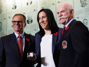Caroline Ouellette, receives her Hockey Hall of Fame ring from Mike Gartner, left, and Lanny McDonald as she was inducted into the Hall on Friday, Nov. 10, 2023.