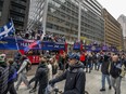 Fans walk along and cheer with the Montreal Alouettes during the Grey Cup victory parade in Montreal on Wednesday, Nov. 22, 2023. Some dreary November weather didn't stop fans from turning up in numbers at the parade on Wednesday.