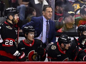 Ottawa Senators head coach stands behind the bench in a game against Pittsburgh. CP