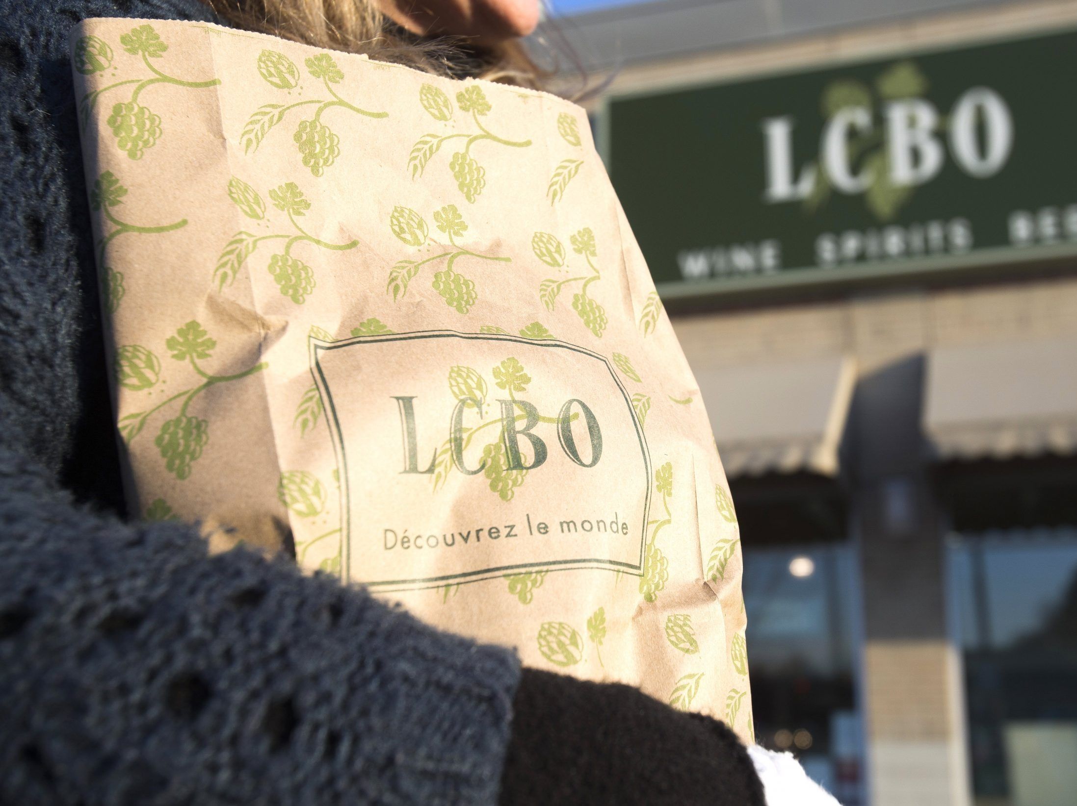 トロントのLCBO店舗で購入したアルコールの入ったバッグを運ぶ女性。