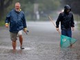 Neighbours trying to clear the water off their street in Elmvale Acres during a summer rain storm