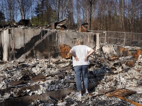 Maureen McGee searches for belongings in the ruins of her family's home after it was destroyed in a wildfire earlier this month in the suburban community of Hammonds Plains, N.S., outside of Halifax on Thursday, June 22, 2023.
