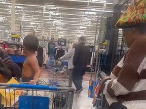 Boy in cart wearing nothing but a diaper while mom texts next to him