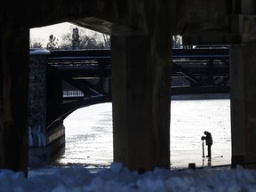A man checks the thickness of the ice on the Rideau Canal near Bank Street in Ottawa Friday. Skaters in Ottawa are hoping that the cold weather the week allows the Rideau Canal to open soon.