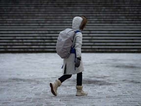 A person bundled up walks during some brief snow in Vancouver on Thursday, Jan. 11, 2024.