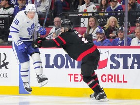 Mitch Marner of the Toronto Maple Leafs jumps in the air as he's checked by Artem Zub of the Ottawa Senators.