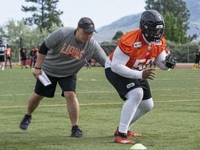 B.C. Lions offensive line coach Bryan Chiu works with Phillip Norman during a blocking drill.