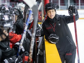 PWHL Ottawa head coach Carla MacLeod leans over the bench at practice.