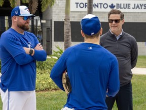 Toronto Blue Jays manager John Schneider, left, and GM Ross Atkins, right, chat with outfielder Daulton Varsho