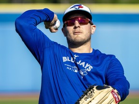 Toronto Blue Jays outfielder Daulton Varsho tosses a ball to a fan during spring training in Dunedin, Fla.