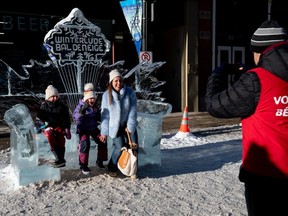 A family poses for photos on a chair sculpted from ice during the final day of Winterlude events on Sparks Street on Family Day, Monday, Feb. 19, 2024.