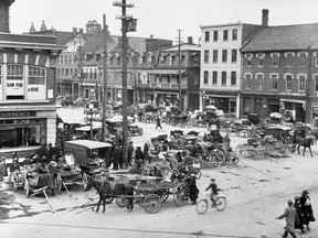 Horse-drawn carriages move people and wares through the ByWard Market, in this early photograph.