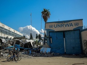 People walk past the damaged Gaza City headquarters of the United Nations Relief and Works Agency for Palestine Refugees (UNRWA) on February 15, 2024, amid ongoing battles between Israel and the militant group Hamas. Several countries -- including the United States, Britain, Germany and Japan -- have suspended funding to the UNRWA agency in response to Israeli allegations that some of its staff members participated in the October 7 attack by Hamas militants.