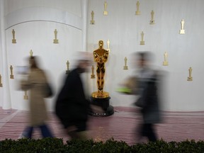 People walk by an Oscars statue on the red carpet ahead of the 96th Academy Awards, Thursday, March 7, 2024, in Los Angeles, Calif.