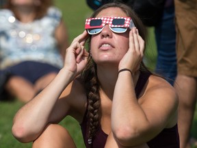 A young woman views the 2017 eclipse with eclipse glasses.