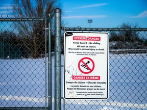 A file photo from 2022 shows a warning sign and fencing at the Mooney's Bay Beach and Park hill.
