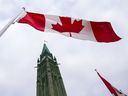 一张资料照片显示，加拿大国旗在国会山和平塔前飘扬。