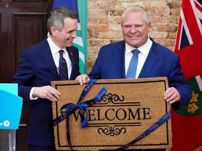 Ottawa Mayor Mark Sutcliffe, left, presents Ontario Premier Doug Ford with a welcome mat as the hold a press conference at Ottawa City Hall on Monday, April 29, 2024.