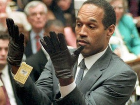 O.J. Simpson shows the jury a new pair of Aris extra-large gloves, similar to the gloves found at the Bundy and Rockingham crime scene 21 June 1995, during his double murder trial in Los Angeles, California.