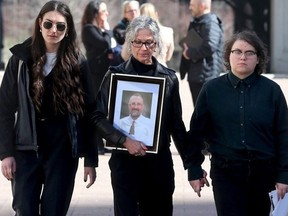 Franco Micucci's widow, Shirlene Byne, clutches a picture of her late husband as she leaves the Elgin Street courthouse Thursday with daughters Daisy Micucci, right, and Nadya Byne, left. The family was in attendance for the sentencing hearing of Tevon Bacquain.