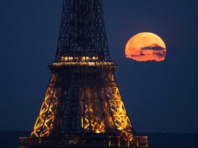 This photograph taken in Paris on April 23, 2024, shows the April's full moonset, also known as the Pink Moon, seen behind the Eiffel Tower.