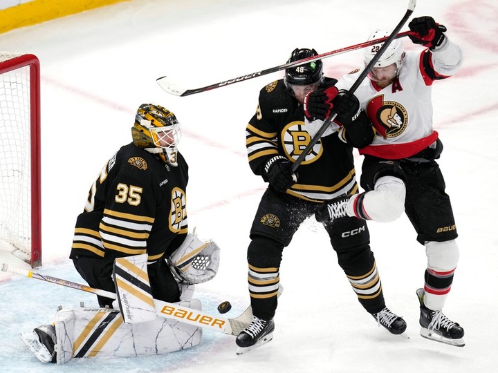  The Ottawa Senators’ Claude Giroux, beside Bruins defenceman Matt Grzelcyk, steps out of the way of the puck as goaltender Linus Ullmark makes a save during the first period in Boston on Tuesday night.