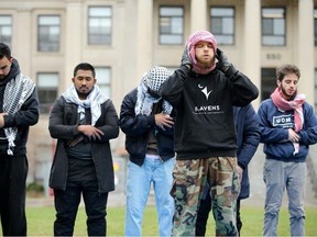 Six young men go about their daily prayers on the lawn of Taberet Hall on Tuesday. A gathering of about 20 protesters was set up outside Tabaret Hall at the University of Ottawa