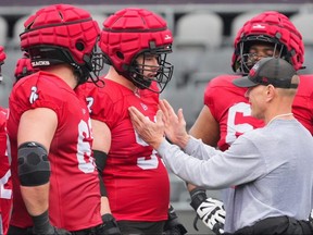 Ottawa Redblacks centre Cyrille Hogan-Saindon (centre) and other offensive linemen listen to offensive line coach Pat Perles during a team workout earlier this month.