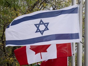 The flags of Canada and Israel fly at half mast at a community building on Wednesday, Oct. 11, 2023 in Ottawa.