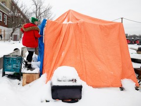 A file photo from January shows a tent resident working to clear snow and ice buildup on the roof of her tent.