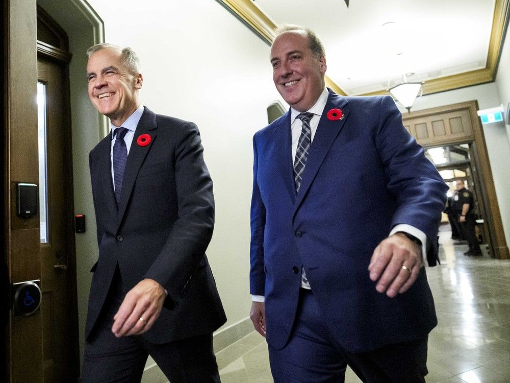 Prime Minister Mark Carney walks with MP Chris d'Entremont, who crossed the room from the Conservative caucus to join the Liberals, at a Liberal caucus meeting on Parliament Hill on Wednesday, November 5, 2025.