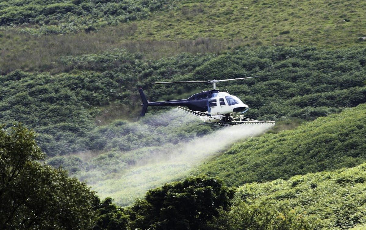 a helicopter applies a herbicide spray in a forested area. the department of environment announced approvals for spraying 954 hectares of privately owned woodland with visionmax, a herbicide with glyphosate (also used in roundup) as an active ingredient. - 123rf
