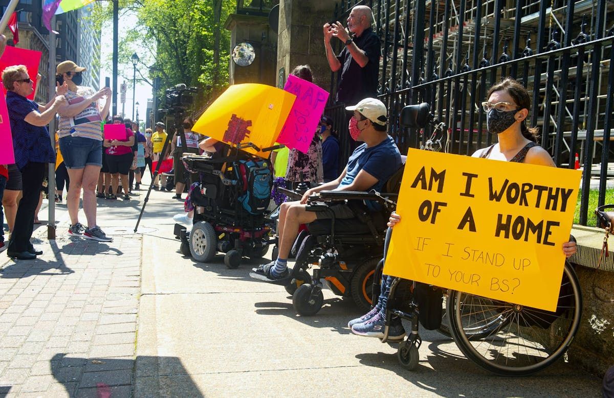  april hubbard holds a sign as she attends a disability rights coalition rally outside province house in 2021.
