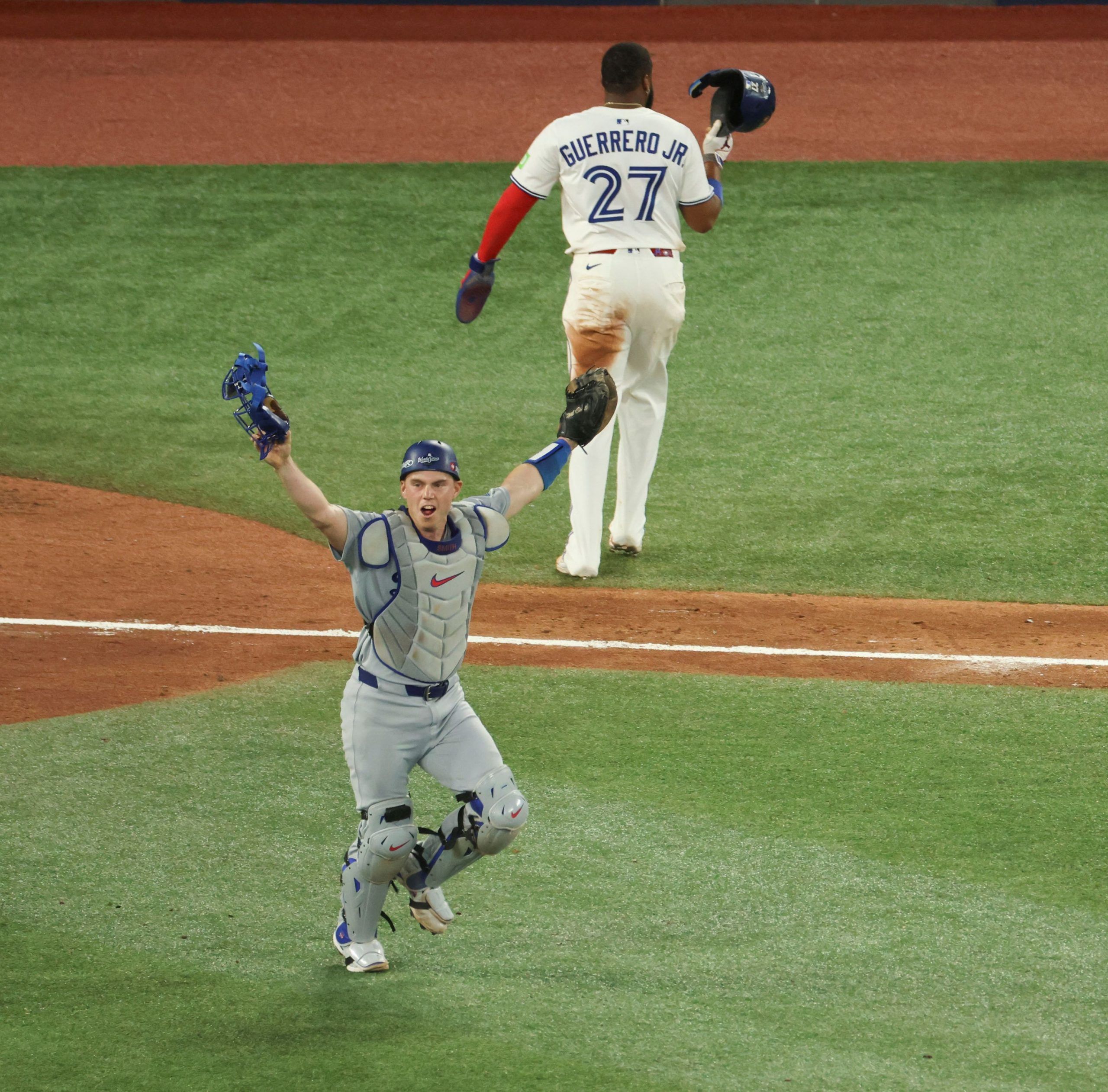 los angeles catcher will smith celebrates the dodgers' 5-4 win over the toronto blue jays in game 7 of the world series as toronto's vladimir guerrero jr. walks off the field.