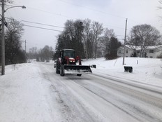 Snow plow driving down snow and ice covered road