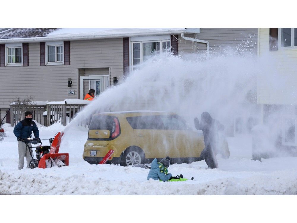 Lucas Ruiz-Gil puts Erik Johansen, right, under a snow blast while clearing the driveway of the Johansen household in Eastern Passage on Tuesday. Looking on is Elsa Johansen.
