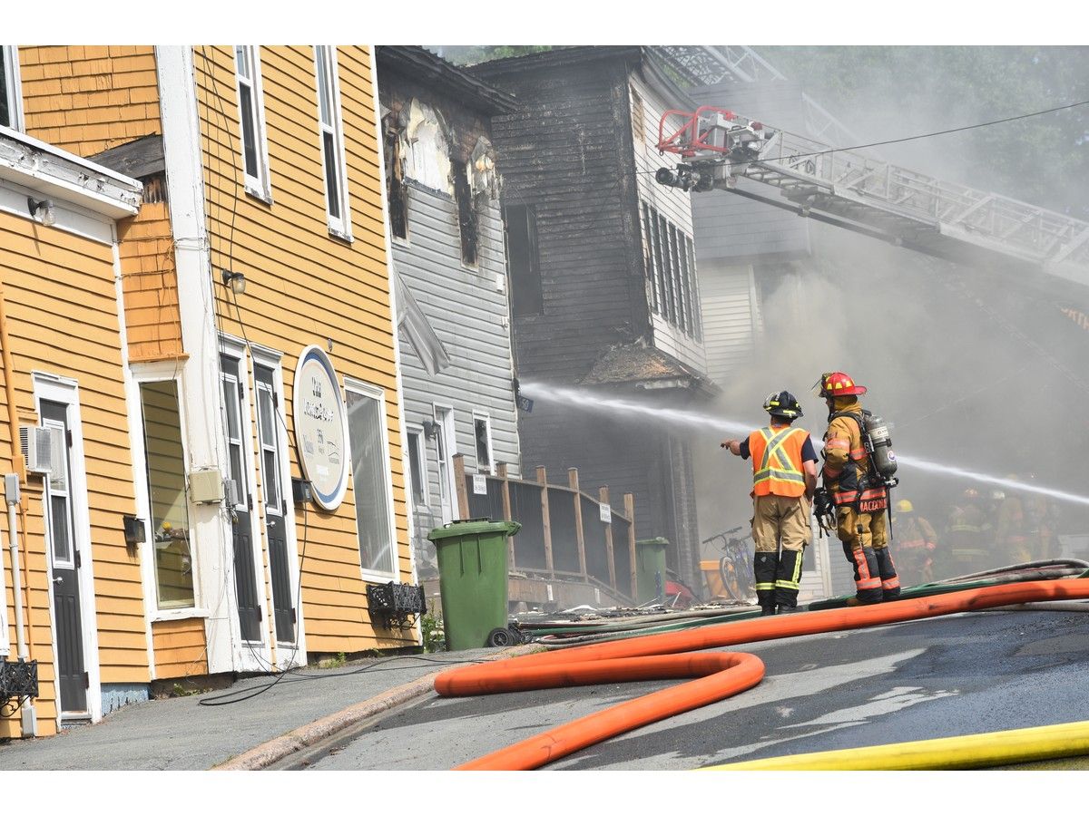 two firefighters look on as crews battle a structure fire in downtown bridgewater on wednesday.