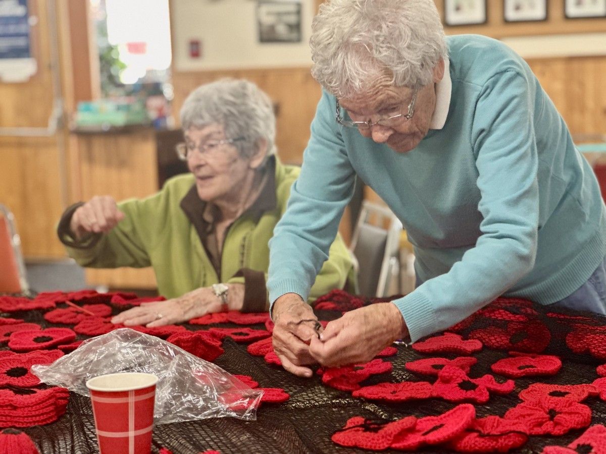93-year-old volunteer Rose Fox, right, ties knitted and crocheted poppies onto netting. The poppies will become a display in front of the Wedgeport Legion hall. TINA COMEAU