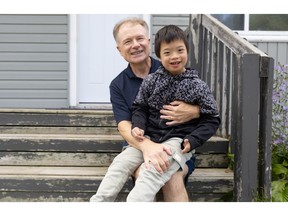 Perry DeNure with his youngest son Benjamin, 9, on the steps of their Dartmouth home on Friday, Oct. 9, 2026.
