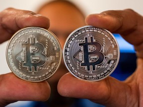 FILE: A picture taken on Feb. 6, 2018 shows a person holding a visual representation of the digital crypto-currency Bitcoin, at the "Bitcoin Change" shop in the Israeli city of Tel Aviv. /