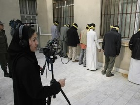 Iranian journalists film a row of accused drug smugglers at a police station in Iran, 03 January 2006.