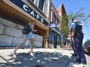 FILE - City bylaw officers and Toronto police guard the entrance of the Bloor St. W. location of the CAFE cannabis dispensary, a chain of illicit pot retailers in Toronto, Ont. on Thursday, July 18 2019.