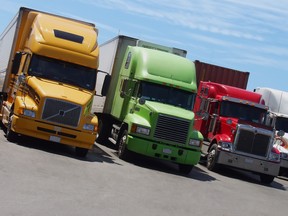 FILE - Yellow, green and red semi-trailer trucks stand side-by-side at a rest area in North America.