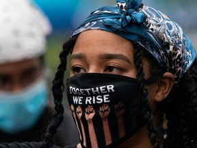 FILE: "Together we rise" is written on the mouth and nose protection of a demonstrator during a Black Lives Matter protest on June 17, 2020 in the Harlem neighborhood of New York City.